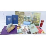 A silver gilt coin, two £5 coins in commemorative packets, two first decimal coins folders,
