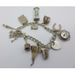 A silver charm bracelet with charms including Concorde, compass and £1 note,