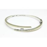 A white metal and diamond bangle, approximately 0.40 carat diamond weight, 18.