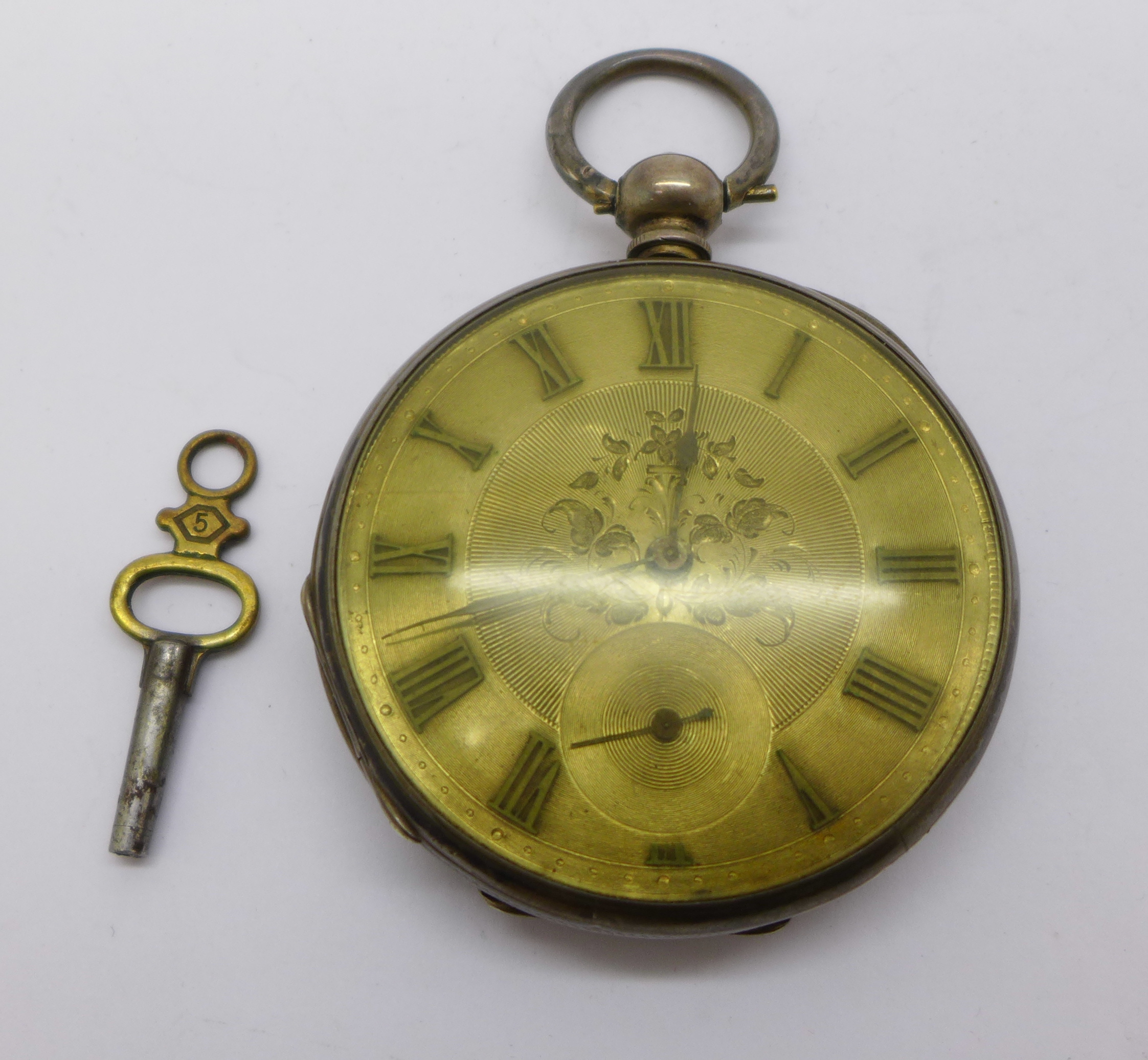 A silver pocket watch with silver dial and key