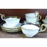 Four Aynsley cups and saucers in midnight blue and gilt decoration with one extra side plate,