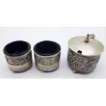 A silver three piece cruet set with scenes of village life, hallmarked Birmingham 1911,