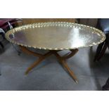 A brass oval coffee table on teak stand