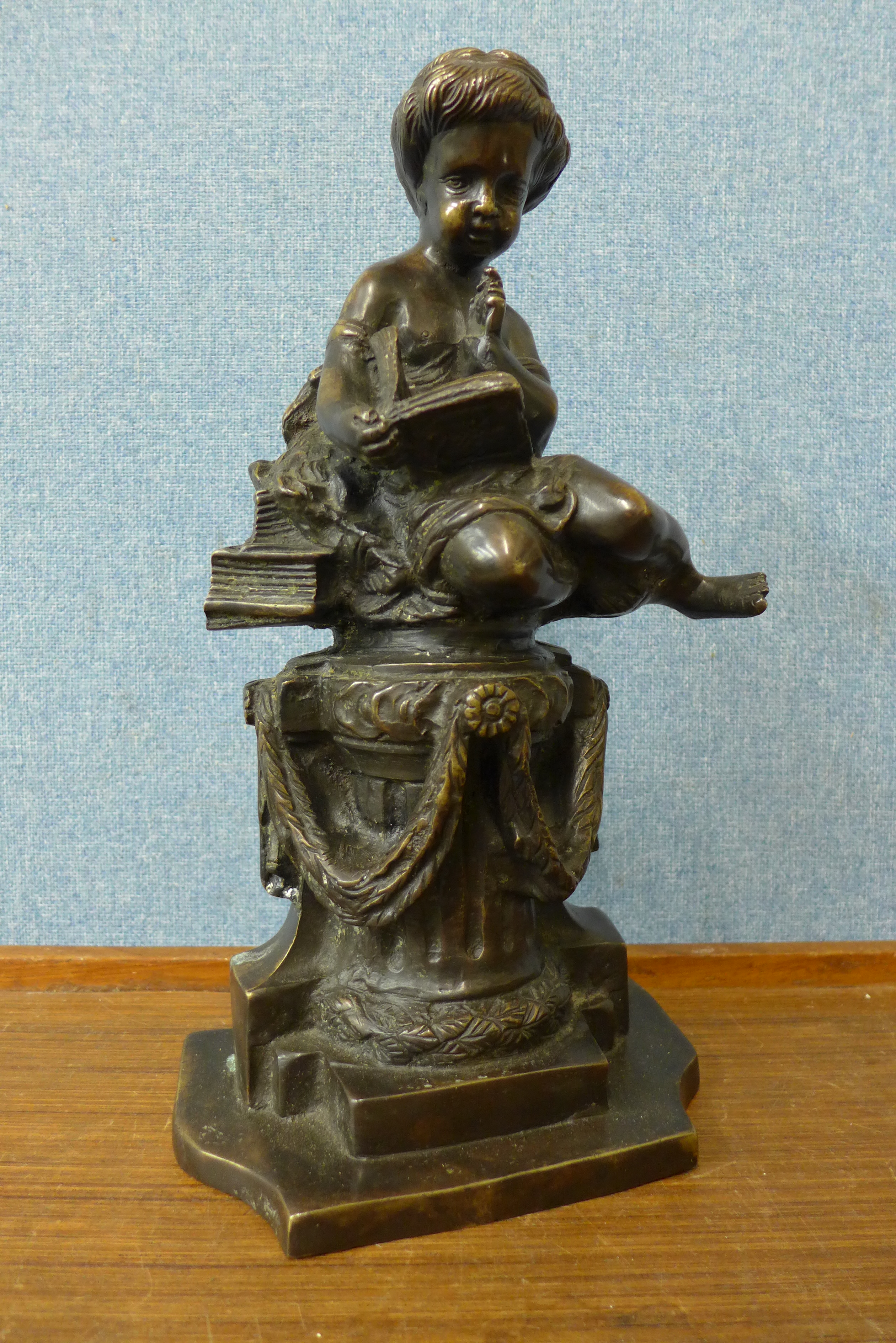 A French style bronze figure of a boy sat on a pedestal