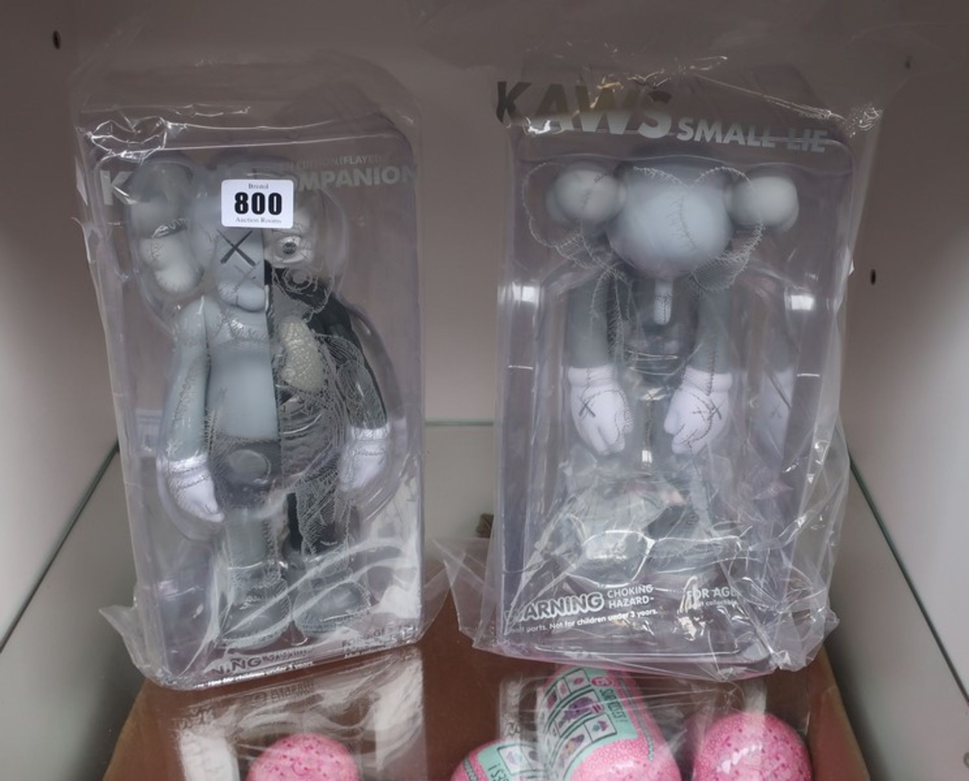 An as new Kaws small lie collectible (Grey) and an as new Kaws open edition companion (Flayed).