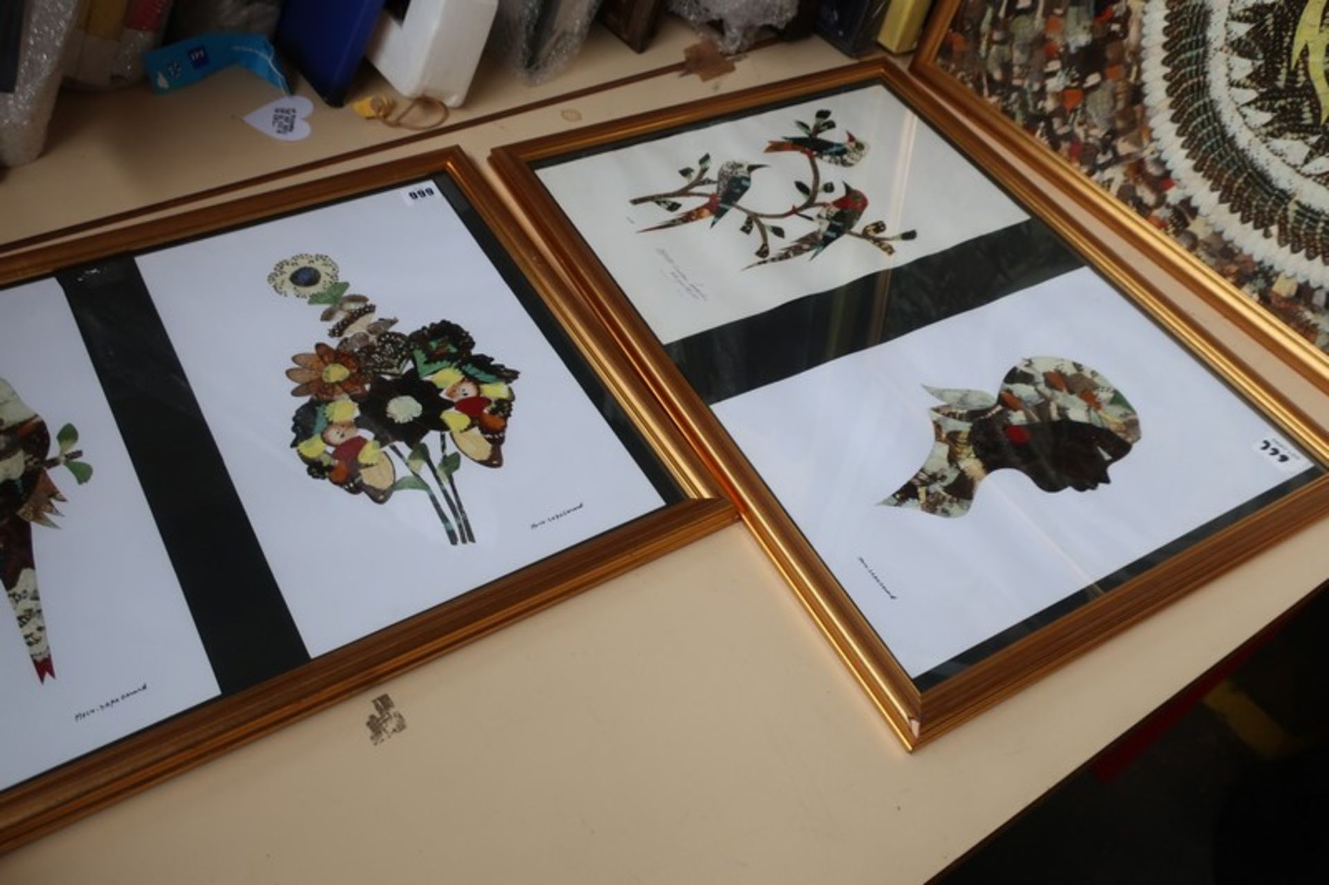 Three framed butterfly wing pictures; one of a lion, the remaining two with flowers and a side