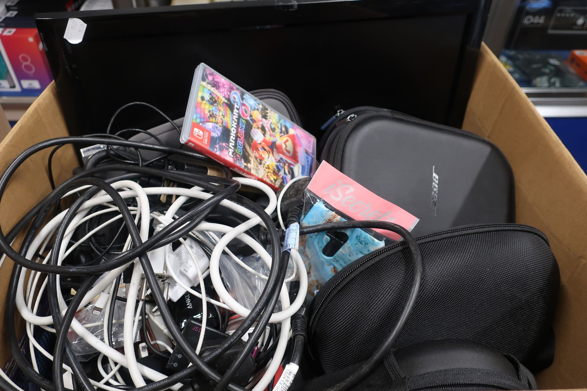 A box of assorted pre-owned small electrical items, chargers, cables and cases.