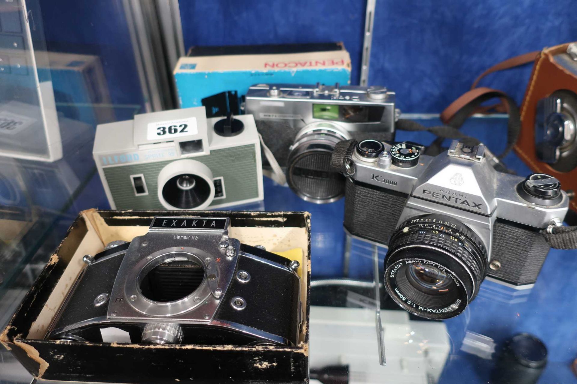 Four vintage film cameras; an Asahi Pentax K1000 camera with a SMC Pentax-M 50mm F2 prime lens, a