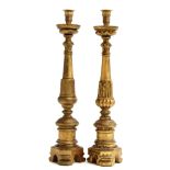 A pair of giltwood altar candlesticks, probably Italian, on cylindrical stems, each decorated with