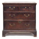 A small George II oak chest of two short over two long drawers, with swan neck handles, raised on