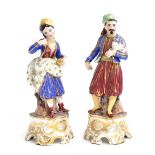 A pair of French porcelain Turkish figurines, the gentleman holding a cat, the lady carrying a small