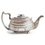 An ornate silver teapot of oblong form with chased silver handle, the whole chased with foliate