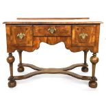 A William and Mary walnut lowboy with quarter veneer top above three small drawers, cross and