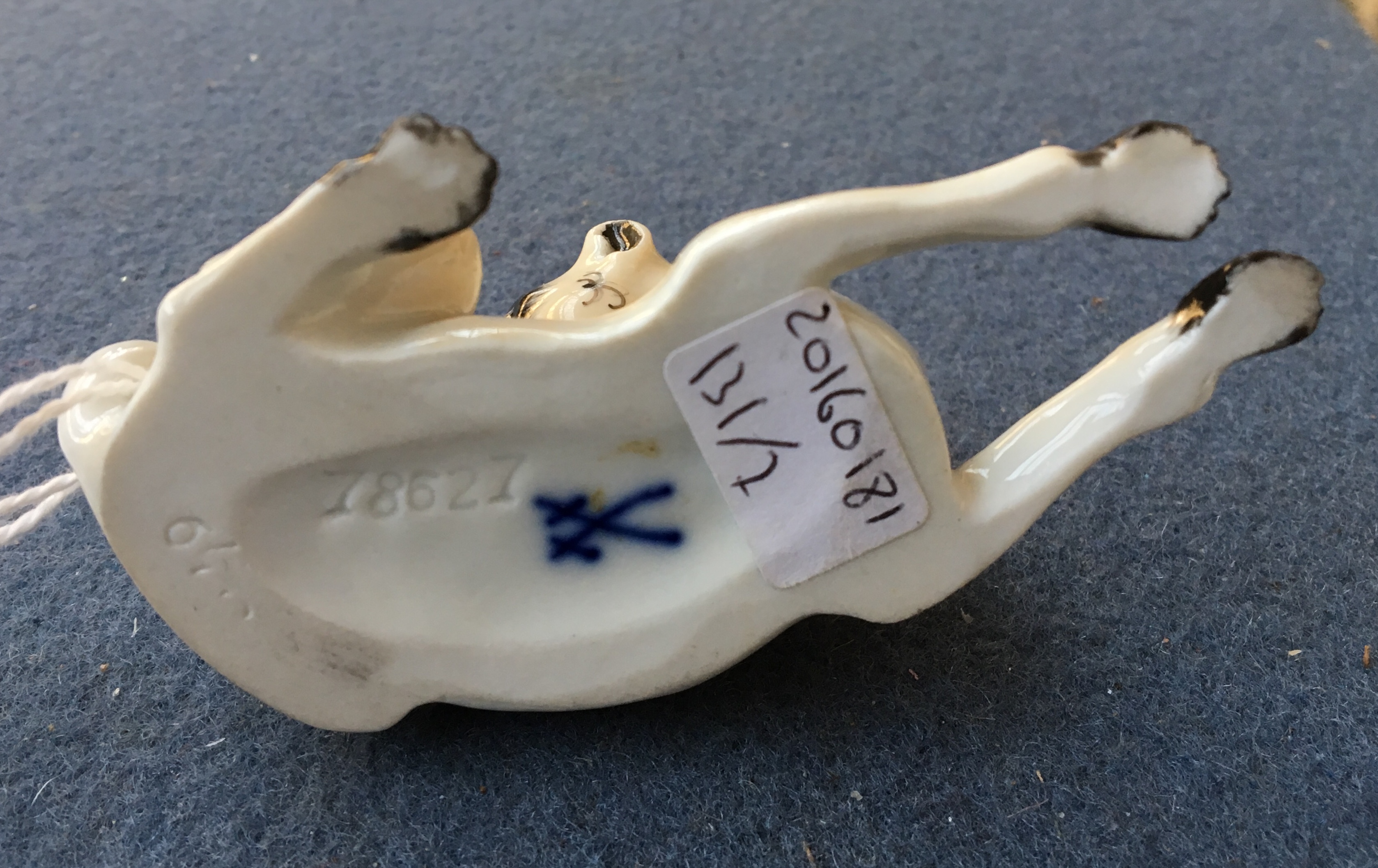 A Meissen model of a pug dog, after J J Kändler, lying down and cleaning his back, wearing a blue - Image 2 of 2