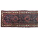 A long madder and indigo runner rug, the central lozenges surrounded by a triple border, 105x480cm
