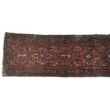A long runner rug in tones of red, brown, and indigo, with accents of white, surrounded by a