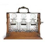 A 19th century oak cased three decanter Tantalus by Betjemann's having silver plated mounts and