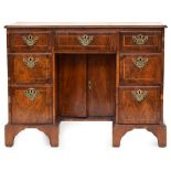 A Georgian walnut and featherbanded kneehole desk, the top with re-rentrant corners above three