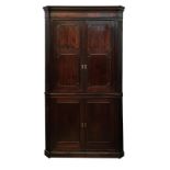 A Georgian mahogany two piece standing corner cupboard, the two pairs of cupboard doors with applied