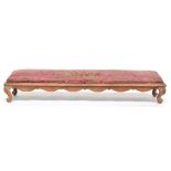 A Louis XVI style fruitwood long upholstered footstool, with swag frieze, on short carved cabriole