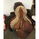 A vintage felt backed racing saddle marked Geo. Parker; together with three English hunting saddles