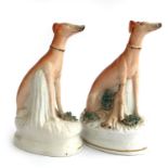 A pair of Staffordshire figurines of seated greyhounds with captured quarry, 15cmH