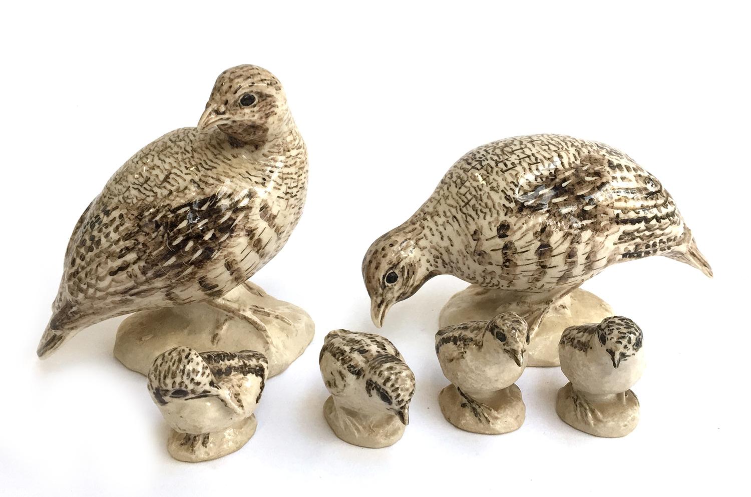 A group of ceramic sculptures of a two adult partridges and four chicks