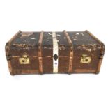 A travel trunk with removable tray and wood and brass bracings, side handles and vintage travel