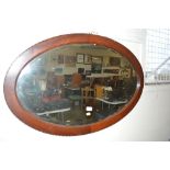A mahogany oval and bevel edge mirror