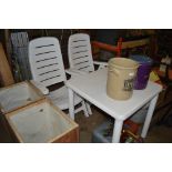 A pair of plastic folding chairs and a white table