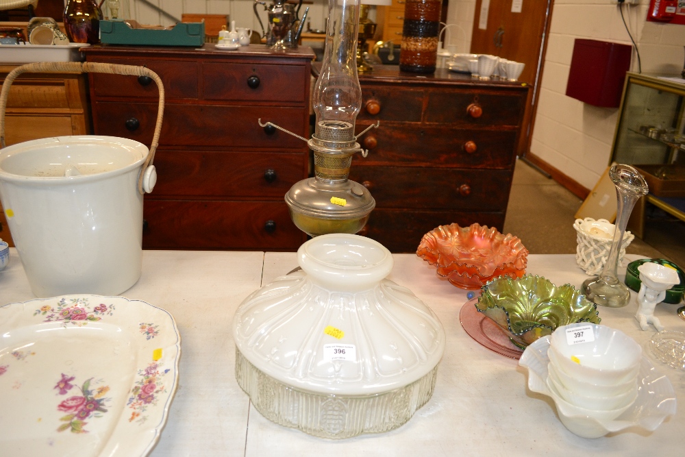 An oil lamp with milk and clear glass shade