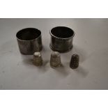 Two silver serviette rings; and three silver thimb