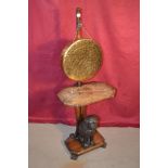 A brass dinner gong on wooden stand with carved do