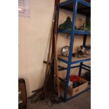 A quantity of long handled tools including rakes,
