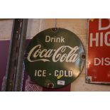 A green "Drink Coca Cola Ice Cold" circular enamel