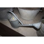 A large galvanised watering can with rose