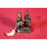 A small iron sculpture of two children with a plat