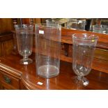 A pair of large etched glass hurricane lamps and a