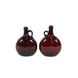 Two 19th Century brown glass flasks, having loop handles, 20cm high