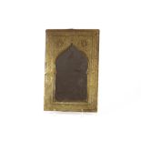 A late 19th/early 20th Century Islamic brass wall mirror, with floral and arabesque scroll