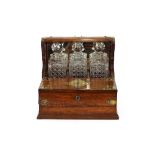 A Victorian oak Tantalus, having brass mounts fitted with three square cut bottles, 36cm wide,