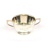 A George V silver circular bowl, with presentation inscription, flanked by stylised loop handles and