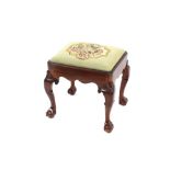 A carved mahogany stool, with needlepoint upholstered drop in seat, raised on carved shell