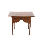 An Antique oak low boy, the over hanging top above three short drawers and a shaped arched frieze,