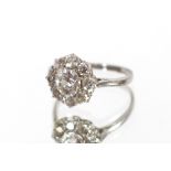 A white metal and diamond cluster ring, set with approx. 1 carat round cut diamond within a surround