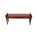 A Regency style mahogany window seat, having scrolled ends raised on turned tapering supports and