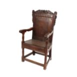 An Antique oak Wainscot chair, the carved roundel decorated back rail above plain panel and solid