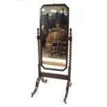 A 1930's oak cheval mirror, raised on a barley twist stand and outswept feet, terminating in
