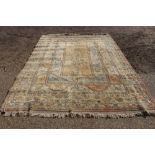 A large Turkish rug, of traditional design with stylised motifs on a beige and pink ground