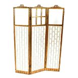 An Edwardian gilt wood three fold boudoir screen, having ribbon tied decoration, glass panels